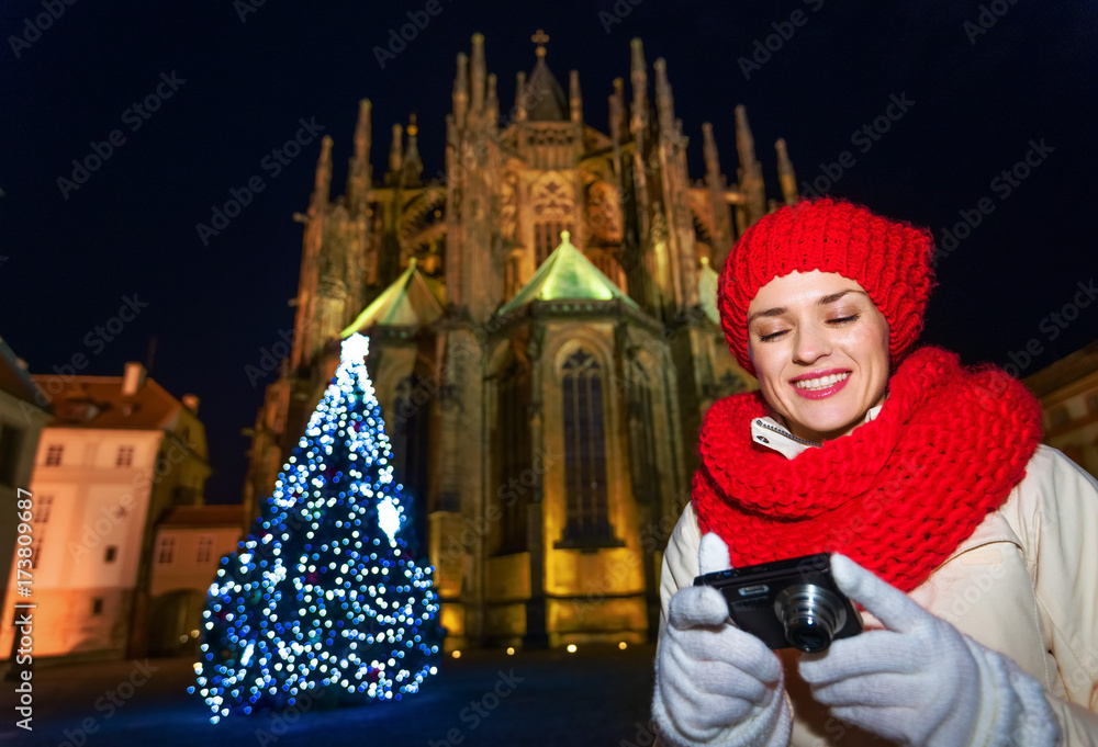 woman near Christmas tree in Prague viewing photos on camera