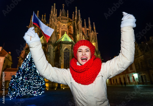 Photography cheerful tourist woman at Christmas tree in Prague rising flag