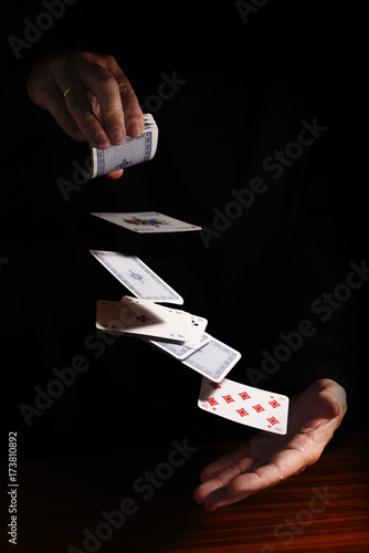 Foto throwing cards from one hand to the other against a black background with copy s