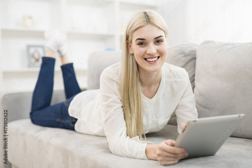 The happy woman lay on the sofa and hold a tablet The happy woman lay on the sofa and hold a tablet