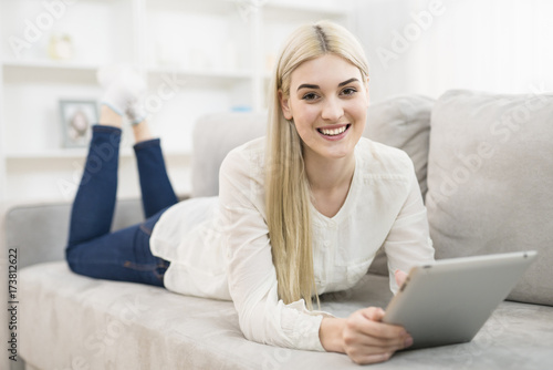 The happy woman lay on the sofa and hold a tablet © realstock1