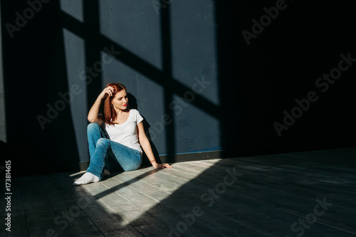 Happy woman portrait siting on gray background wooden floor room window sunny day