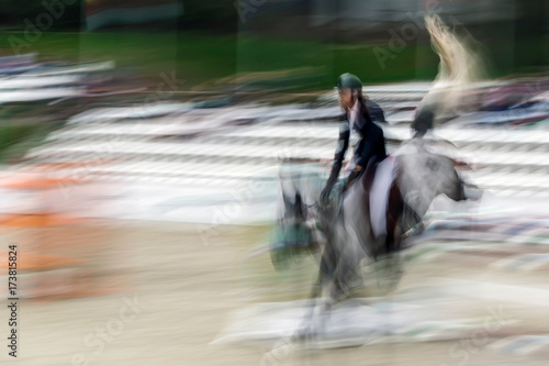 Abstract image with a moving rider and horse at show jumping