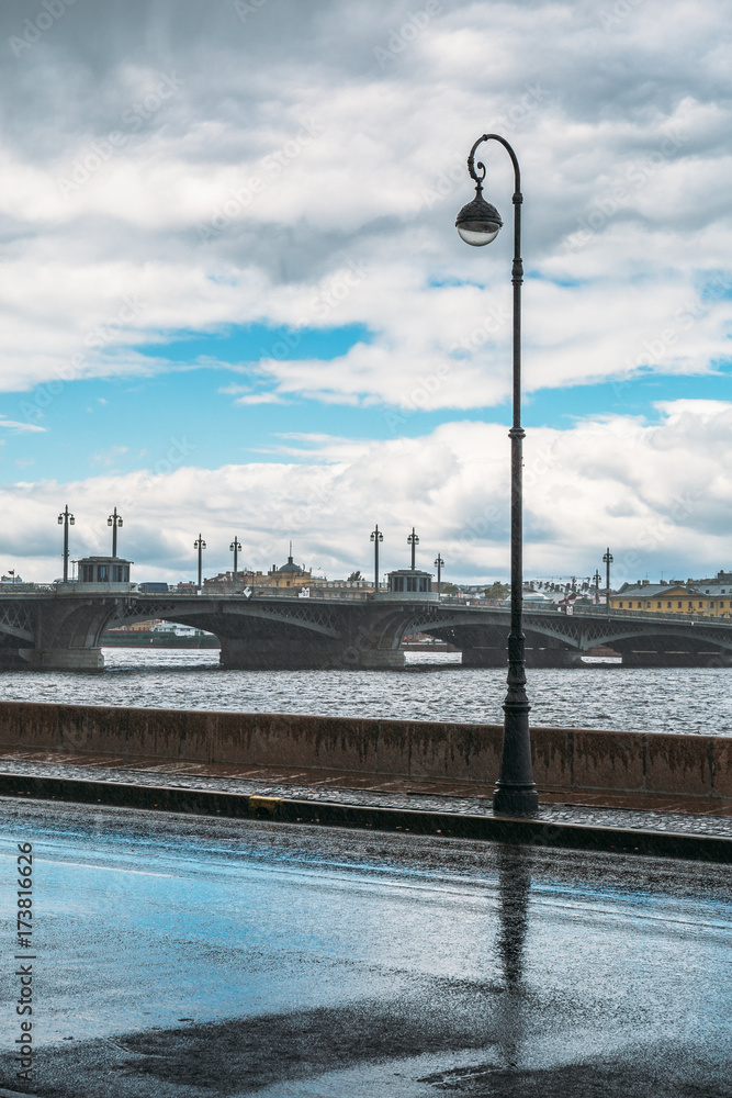 St. Petersburg, Russia after rain, wet embankment, lamppost, river Neva, bridge