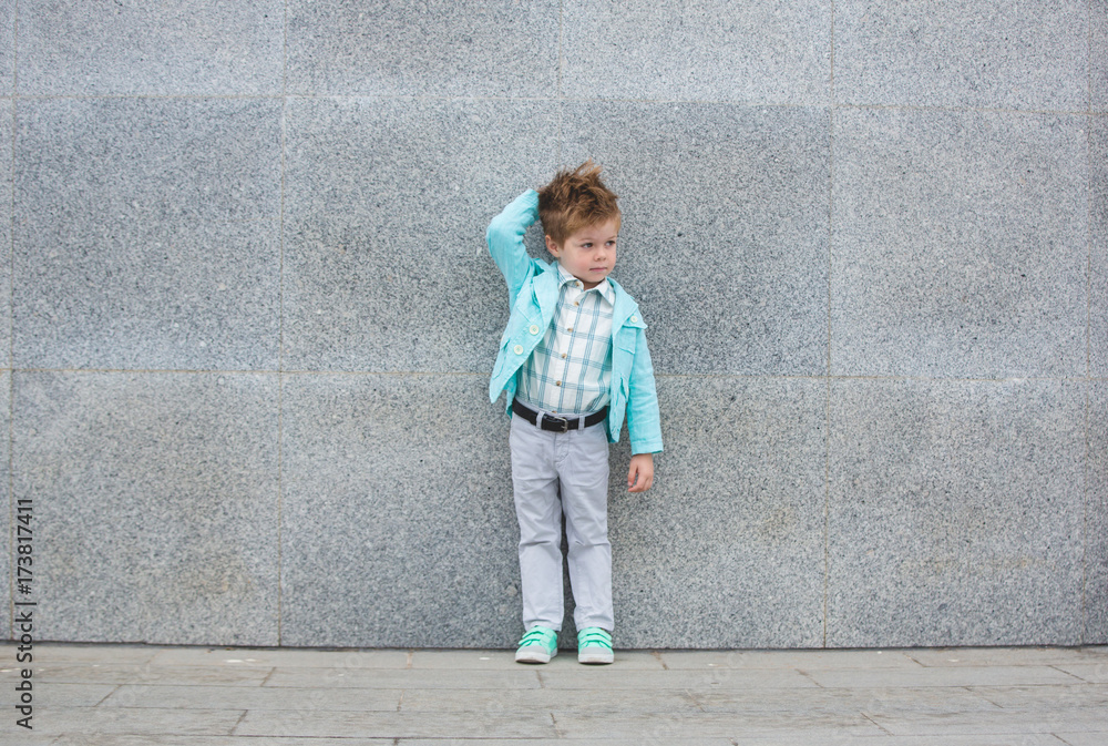 Fashion kid posing near gray wall Fashion kid posing near gray wall