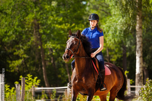 Jockey girl training horse at racetrack in summer