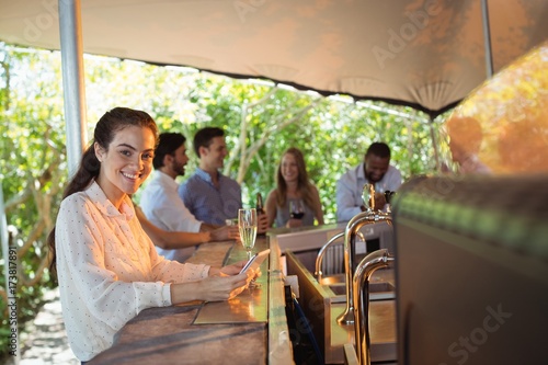 Smiling woman using mobile phone while having a glass of