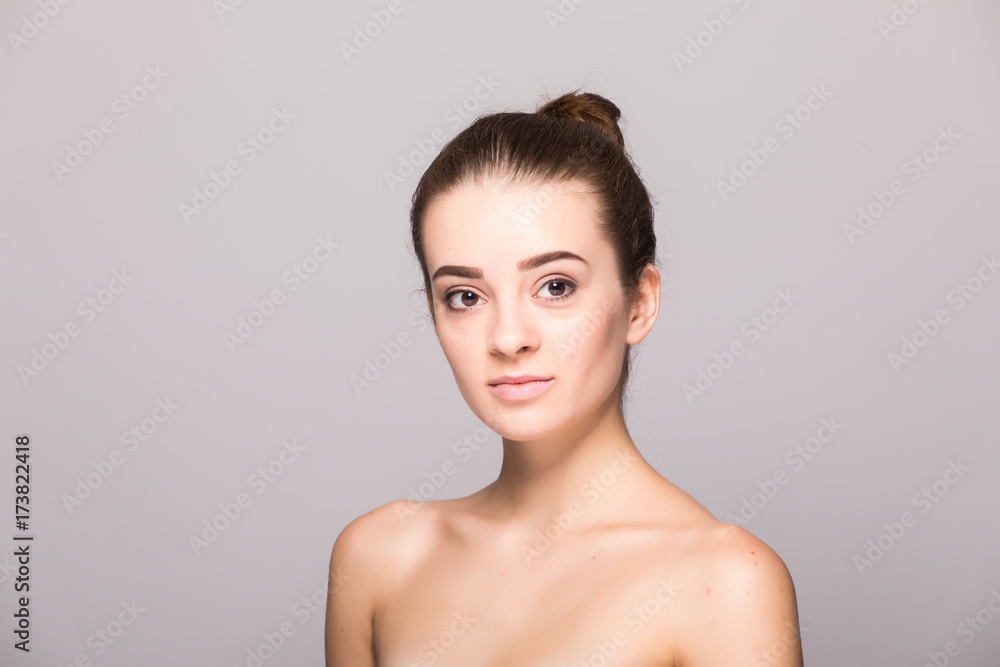 Beautiful woman face close up hand touching face studio on gray Beautiful woman face close up hand touching face studio on gray