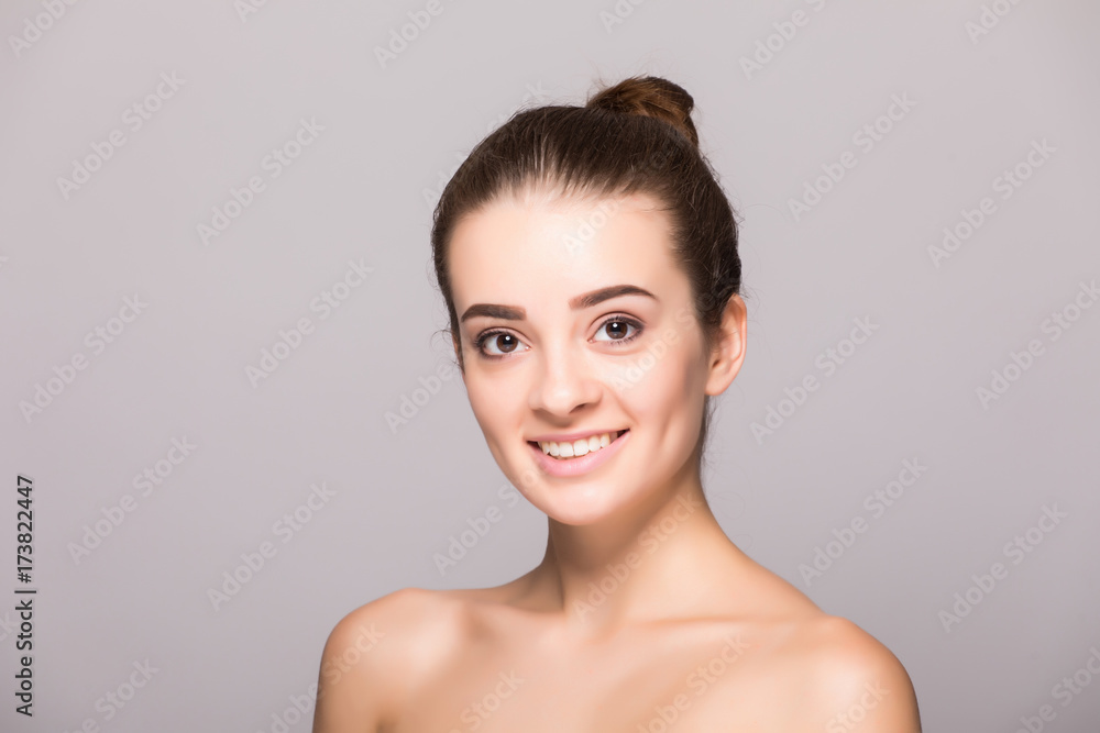 Beautiful woman face close up hand touching face studio on gray Beautiful woman face close up hand touching face studio on gray