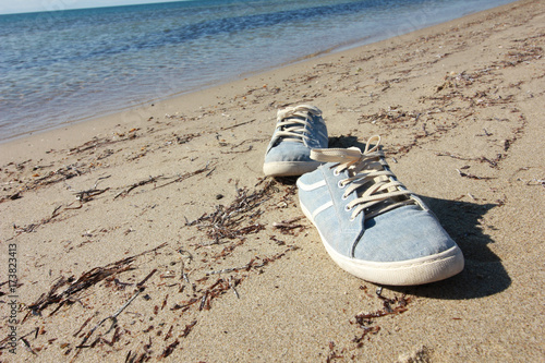 Old blue sneaker on beach. Travel concept.