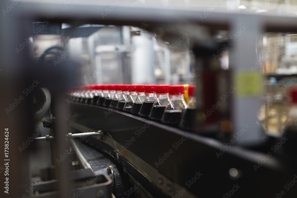 Bottling factory - Black juice or soft drink bottling line for processing and bottling juice into bottles. Selective focus. Bottling factory - Black juice or soft drink bottling line for processing and bottling juice into bottles. Selective focus.