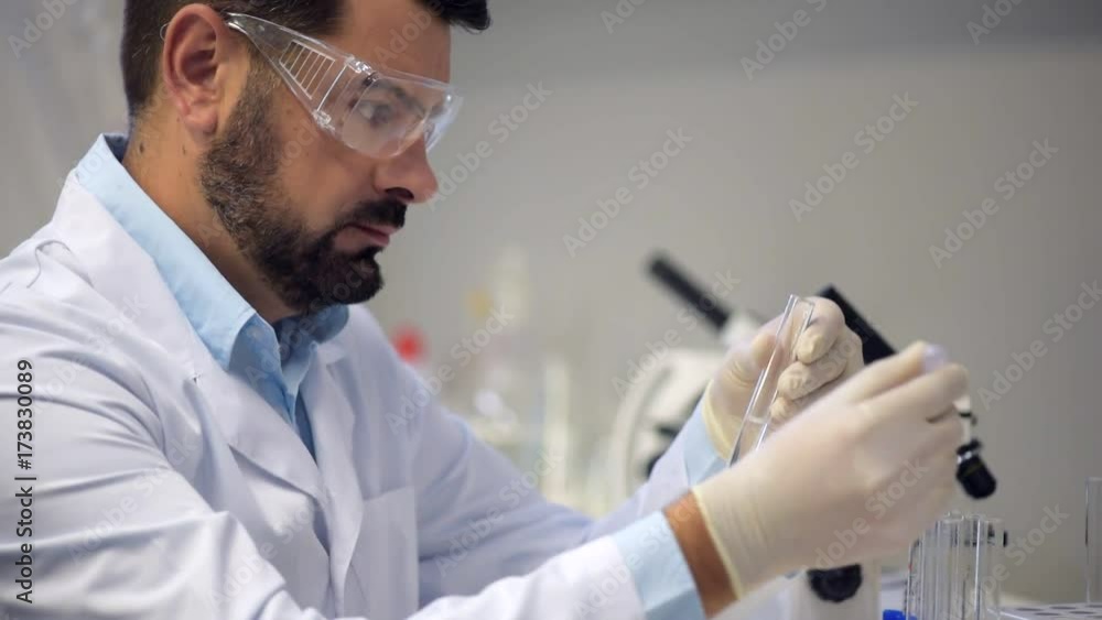 Concentrated chemist dropping liquid into several test tubes Concentrated chemist dropping liquid into several test tubes