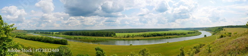 the riverbed from a height, a green field and lots of blue sky with clouds, landscape, panorama