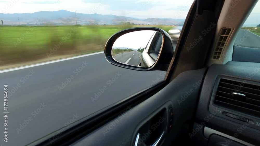 Side view mirror reflection of two-lane winding road, pov Side view mirror reflection of two-lane winding road, pov
