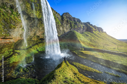 Tourist standing in front of Seljalandsfoss with rainbow around   beautiful amazing landscape from Iceland 