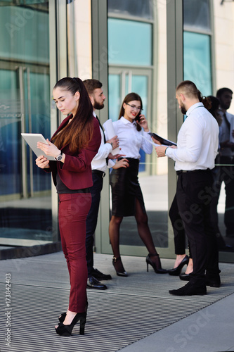 beautiful young girl in business suit with tablet on the background of a glass office building