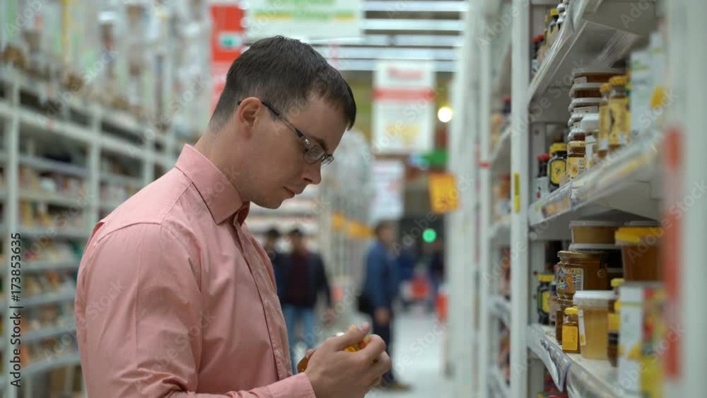 a young guy chooses a honey in a store. a young guy chooses a honey in a store.