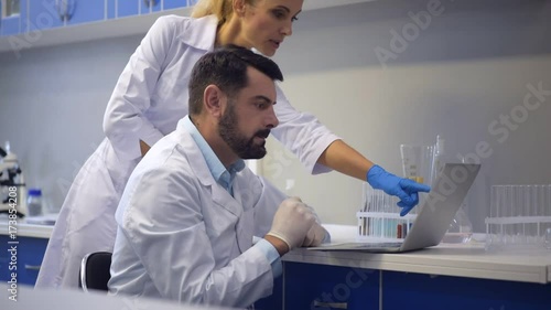 Cheerful scientists working on laptop together