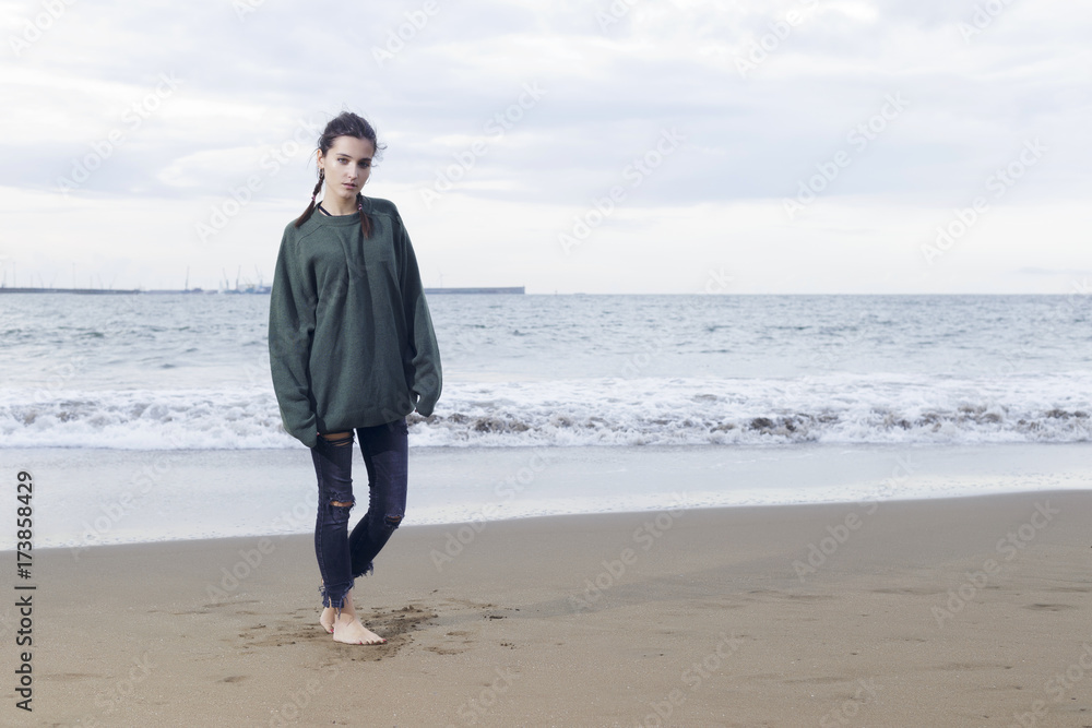 Young pretty woman standing alone on the beach near the sea, waiting for somebody in the ocean. Young pretty woman standing alone on the beach near the sea, waiting for somebody in the ocean.