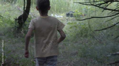 scared Caucasian boy in the forest is frightened and runs, chase after a frightened boy photo