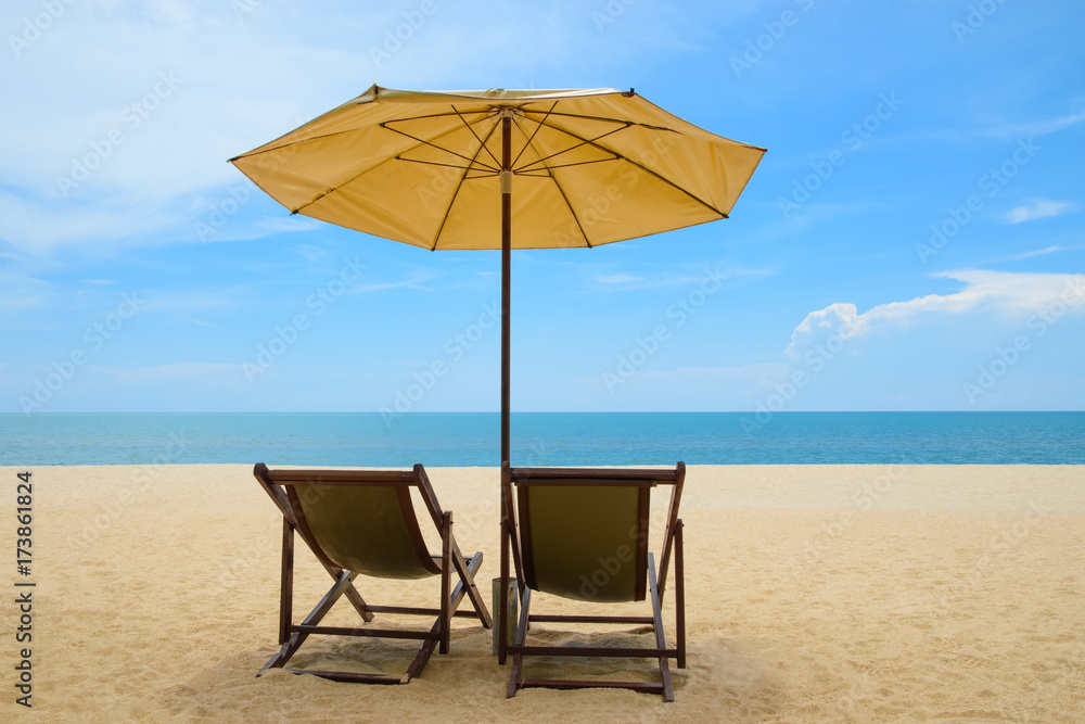 Beach chairs and umbrella on beautiful sand beach with cloudy and blue sky