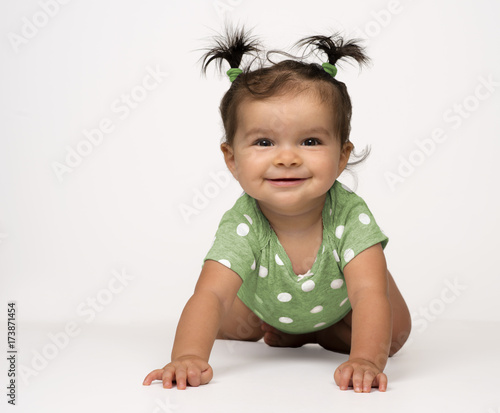 Crawling, mIxed race, baby girl in green onesie on white background