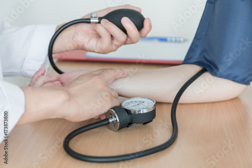 Doctor using sphygmomanometer with stethoscope checking blood pressure  to a patient in the hospital.