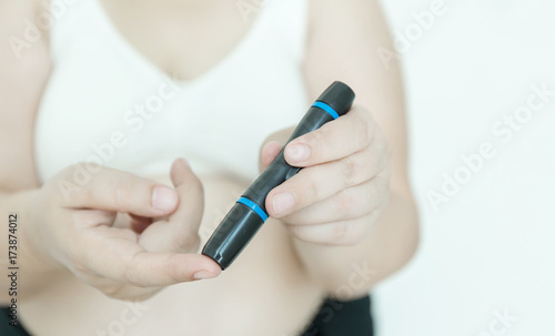 Fat woman with glucometer checking blood sugar level.