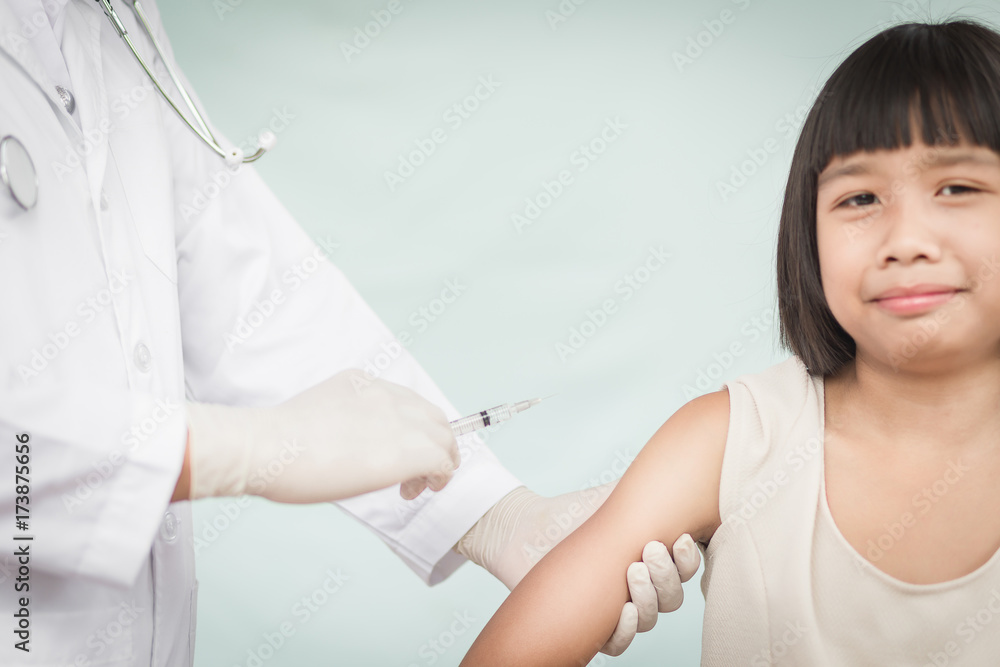 Doctor holding a syringe with a liquid inside next to a girl arm. Doctor holding a syringe with a liquid inside next to a girl arm.