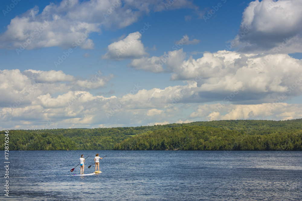 2 girls on a paddle board on a lake