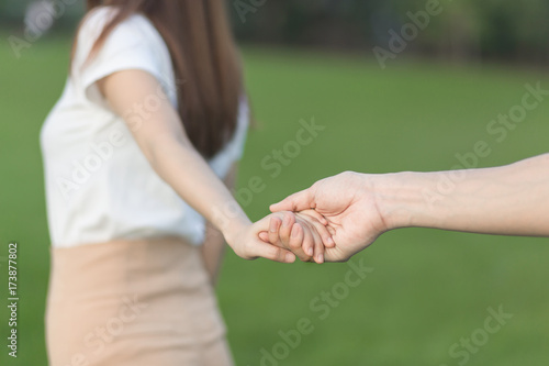 Lovers in the park tenderly hold hands together, blurred background. © chompoo