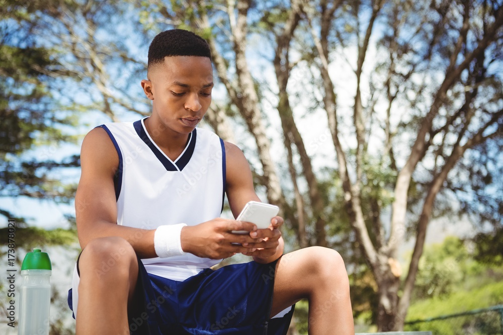 Teenage boy using smart phone while sitting on bench Teenage boy using smart phone while sitting on bench