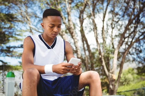 Teenage boy using smart phone while sitting on bench