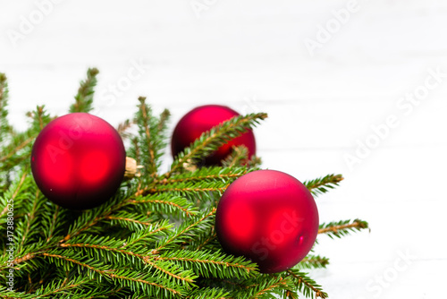 Red ornaments on fir tree, christmas decoration on white wooden background