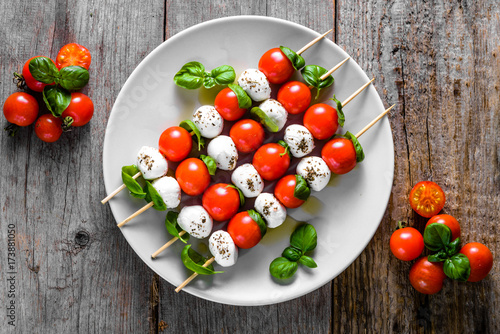 Healthy appetizer - caprese salad with tomato and mozzarella, italian food of mediterranean diet with olive oil dressing, weight loss concept