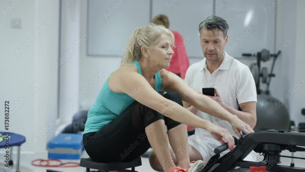 Fitness trainer using smartphone app to train mature female client Fitness trainer using smartphone app to train mature female client
