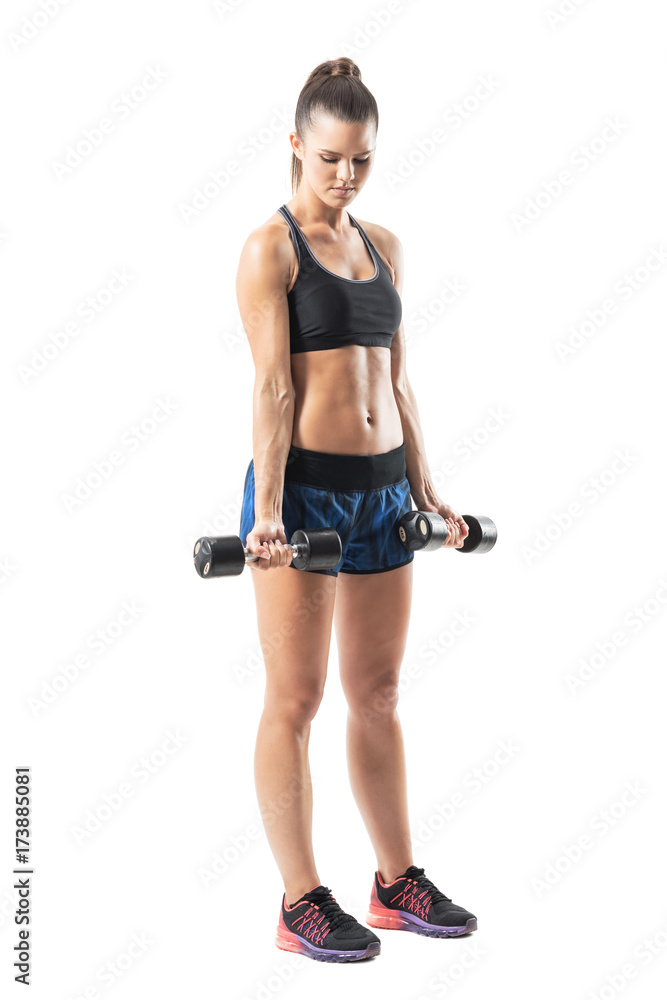Strong muscular female athlete doing bicep dumbbell exercise in extended position. Full body length portrait isolated on white studio background. Strong muscular female athlete doing bicep dumbbell exercise in extended position. Full body length portrait isolated on white studio background.