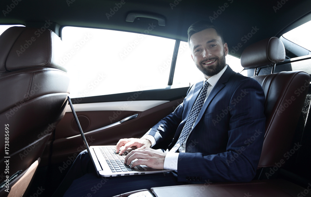 young businesswoman working on her laptop while sitting in the car