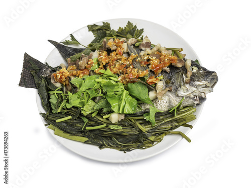 Thai food, Steaming Tilapia fish and streaky pork pour with red hot chilli sauce and steaming vegetables, Celery, Morning glory on white dish. Isolated on white background. Clipping path included.