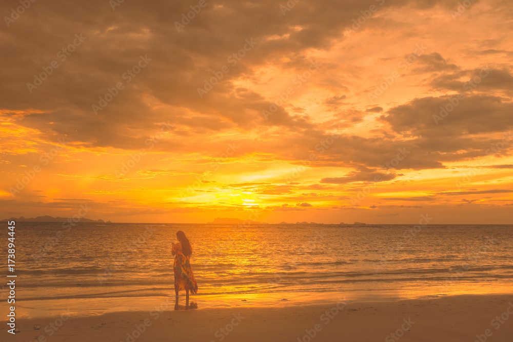 Golden scene on the beach at sunset. Tourist girl sefie herself with sunset at the coast.