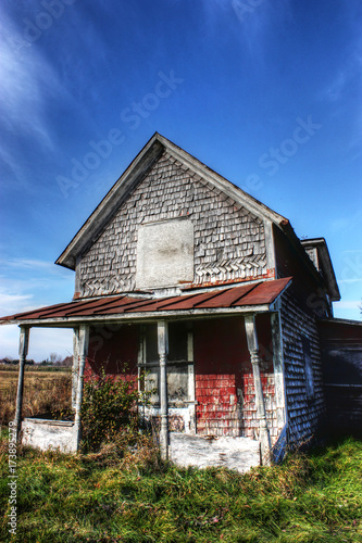 old tiny abandoned house with blue sky and green grass