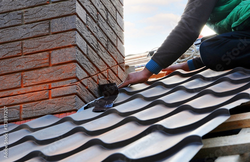 Valokuva Roofer builder worker attach metal sheet to the chimney
