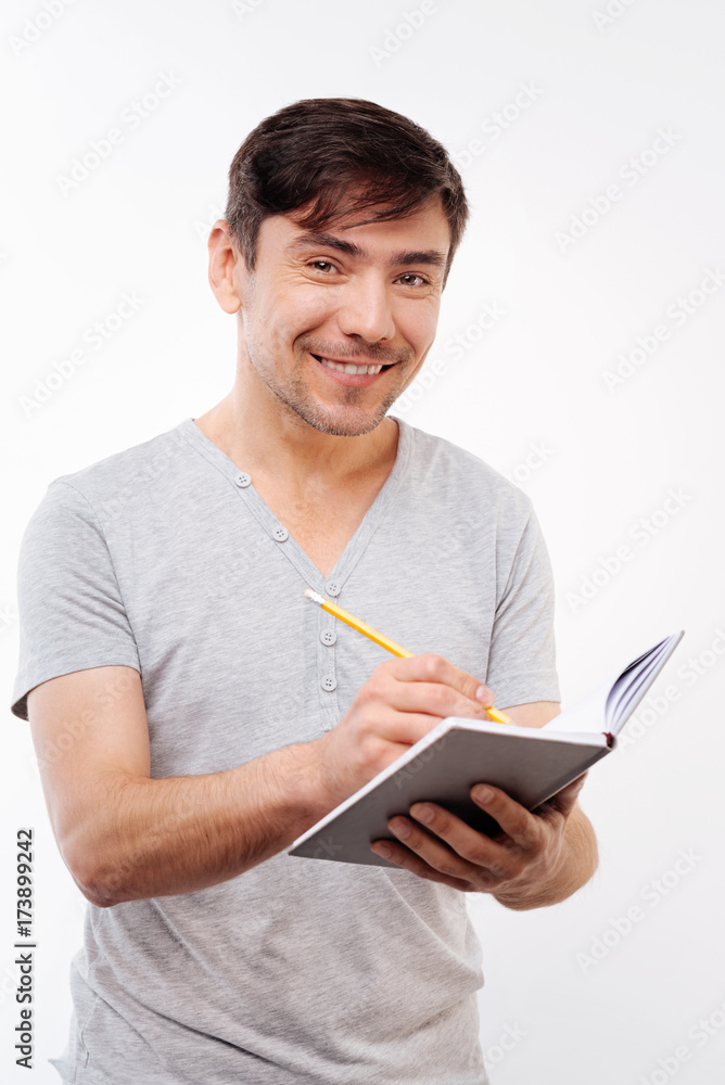 Pleasant bristled man making notes in notebook Pleasant bristled man making notes in notebook