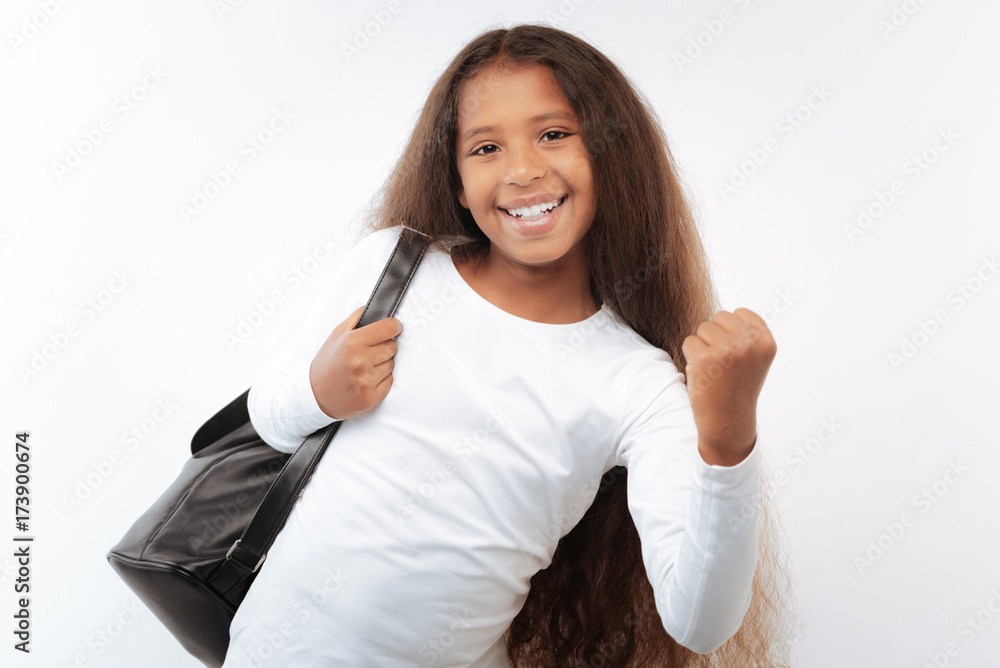 Smiling schoolgirl with a backpack making yes gesture Smiling schoolgirl with a backpack making yes gesture