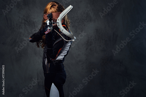 Redhead female Biathlon champion aiming with a competitive gun. photo