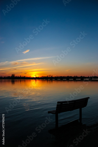 bench on the side of a river with a sunset © S. Lemyre