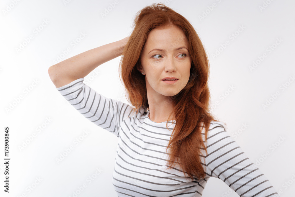 Ginger-haired woman touching back of her head