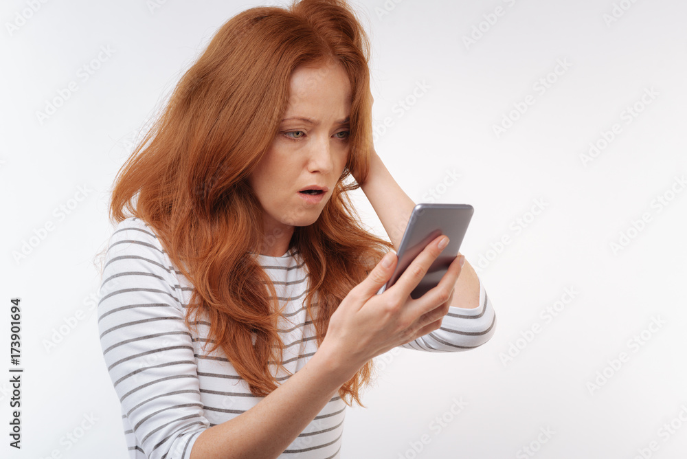 Red-haired woman being shocked after reading message Red-haired woman being shocked after reading message
