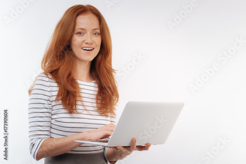 Cheerful red-haired woman holding a laptop