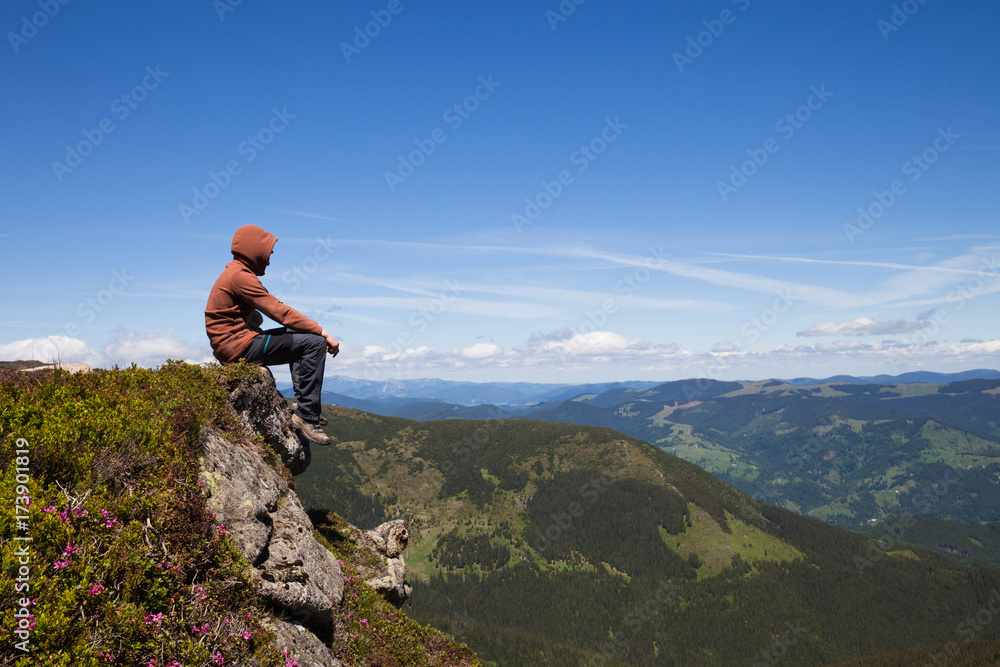 Man sitting on the mountain top and looking at horizon